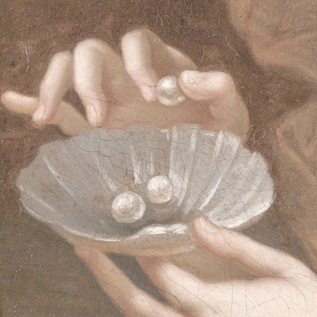 Hands holding a seashell and pearls.